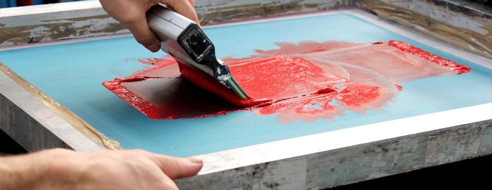 Squeegee pushing ink through the screen onto the fabric